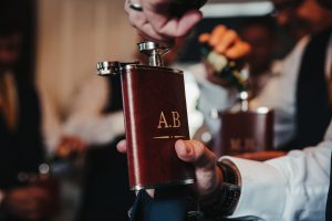 Groomsman opening a hipflask at Peckforton castle
