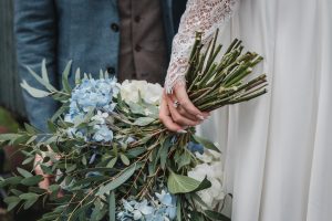 Bride holding her bouquet of flowers down by her side, wedding ring in full view.