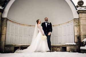 Bride and groom standing side by side laughing hysterically. The background is snowy and wintery. Used to show how relaxed documentary wedding photography can be. 
