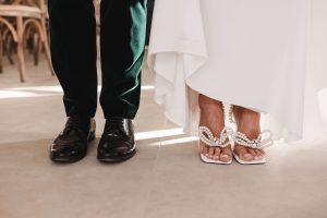 Bride and grooms feet wearing Black loafers and Bride in pearl open toe heals. 