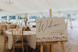 Welcome sign standing on an easel in the Marquee of Crown Hall Farm wedding Venue.