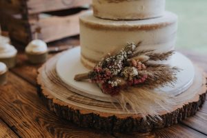 Close up of a white wedding caked with a small bunch of dried flowers on the side. Taken by Sarah Carter photography at Crown Hall Farm wedding venue.
