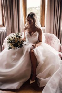 Harlaxton Manor wedding Bride in her wedding dress sits on a pink sofa at Harlaxton Manor wedding venue