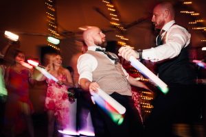 Wedding guests dancing in the background there are fairy lights sparkling.