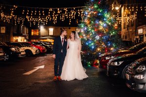 Bride and groom walking holding hands through the centre of Uppington. The town Christmas tree in in the background.