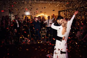 New years eve wedding a bride and groom surrounded by gold confetti falling from above. Both cheering
