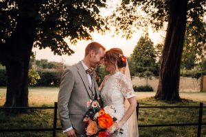 Bride and groom with their heads together trees and grass in the background. Taken at Sandon Manor.