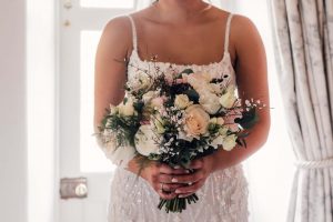 Close up image of a bride holding a bouquet of pink and white flowers