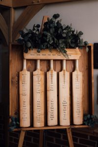 a wedding table plans made out of vintage cricket batts with guests names written in black